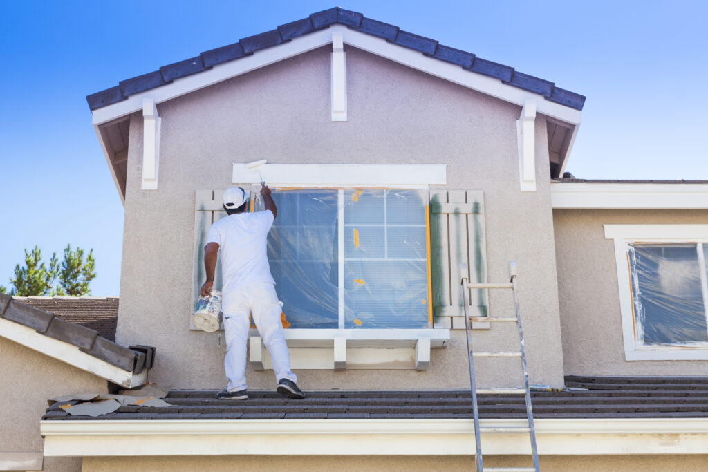 Busy House Painter Painting the Trim And Shutters of A Home. Staining Wood