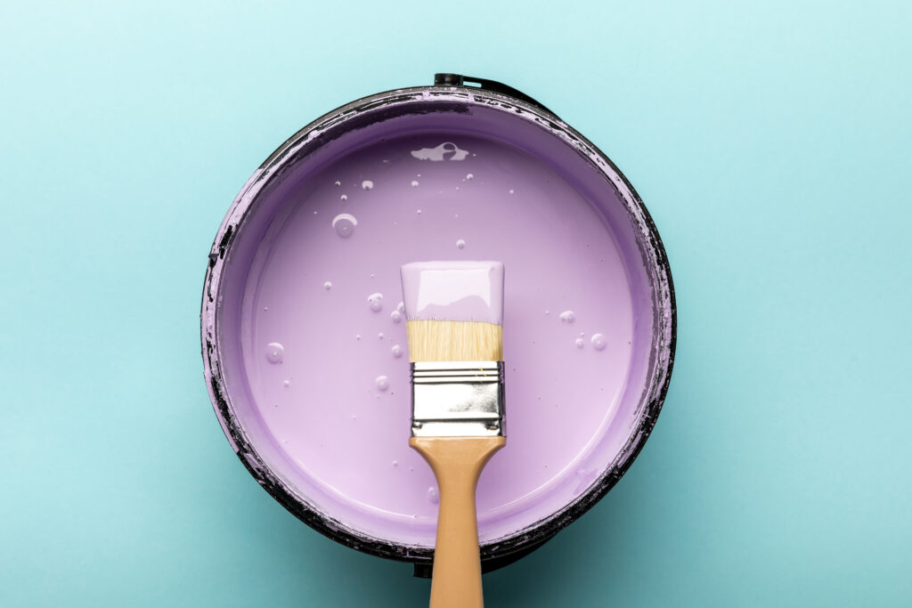 brush over a can of lilac paint on a blue background. composition of paint